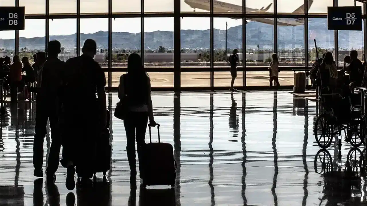 공항 출발 안내판 앞에서 항공권 비용을 비교하는 여행객